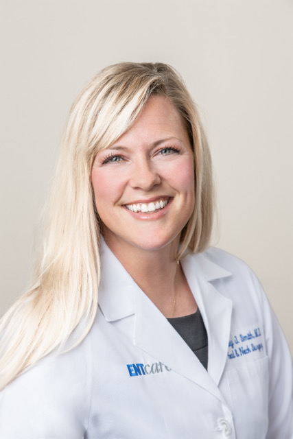 A smiling ENT specialist in a white lab coat.