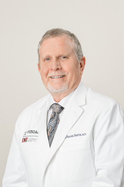 A man in a white lab coat posing for a photo at an ENT clinic in Dothan.
